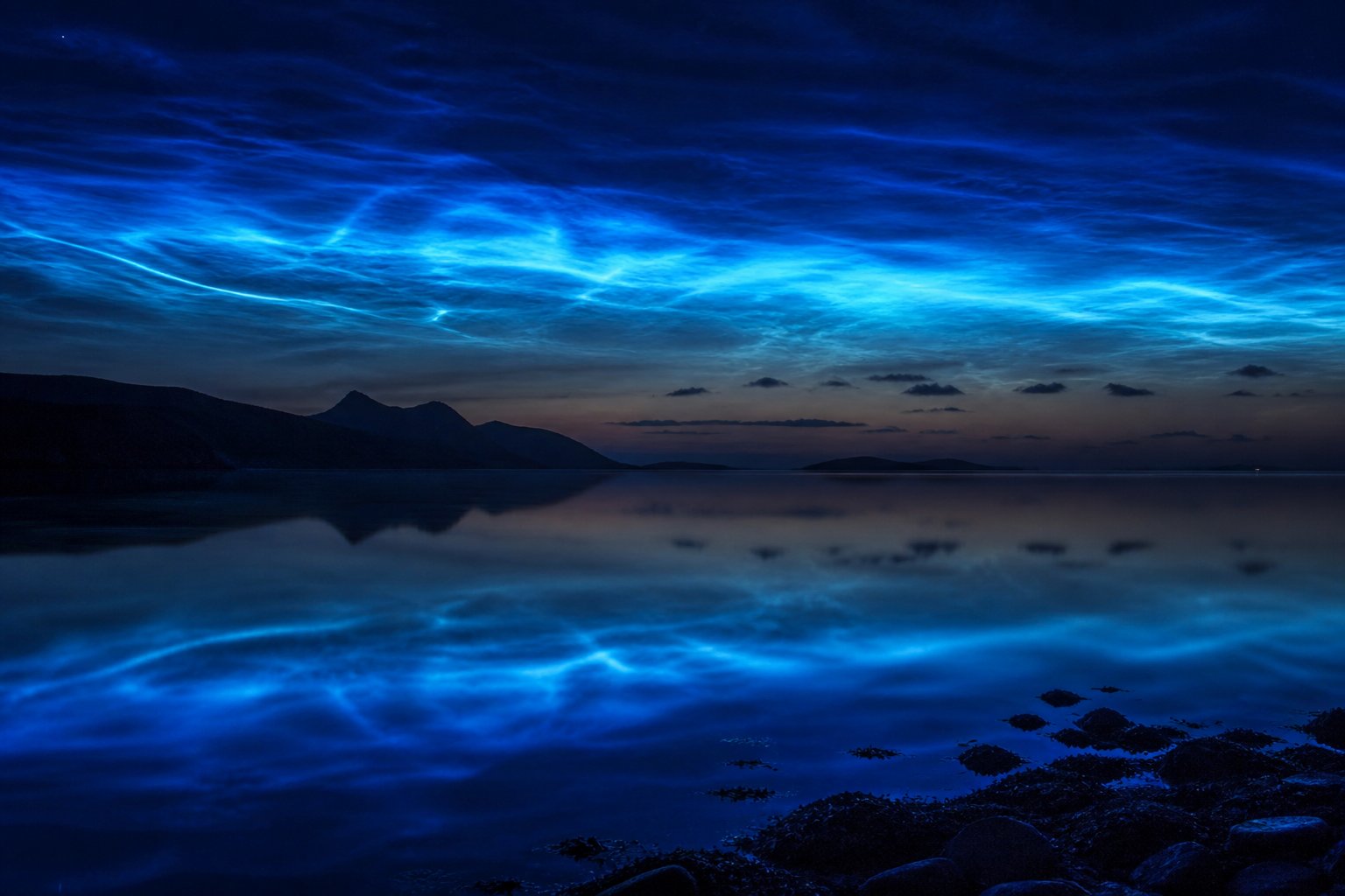 Noctilucent cloud ripples reflected in still water